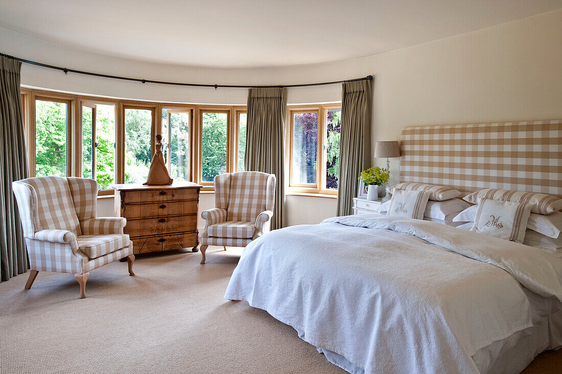 Kombinierte karierte Stühle am Fenster mit passendem Kopfteil im Schlafzimmer eines Hauses in Canterbury, England, UK