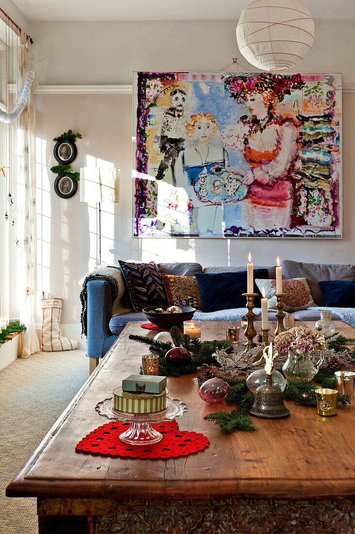 Christmas ornaments on low wooden table with large modern art canvas in living room of Forest Row home, Sussex, England, UK