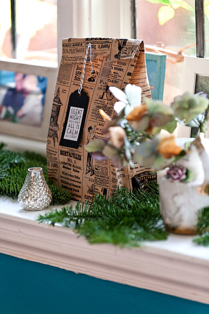 Gift bag and Christmas decorations on window sill in Forest Row family home, Sussex, England, UK