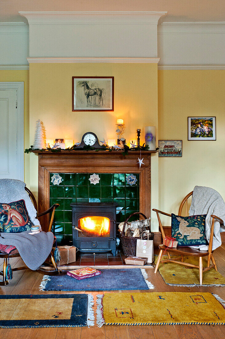 Wooden chairs and lit woodburner in Forest Row family home, Sussex, England, UK