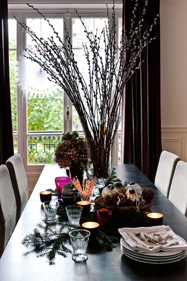 Christmas decorations and tableware with lit tealights on dining table in Paris apartment, France