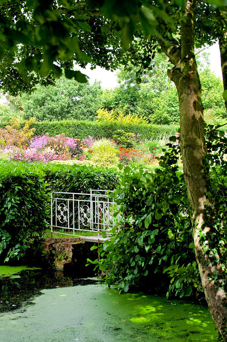 Schmiedeeiserne Brücke über einen Bach in einem Landhaus in Suffolk, England UK