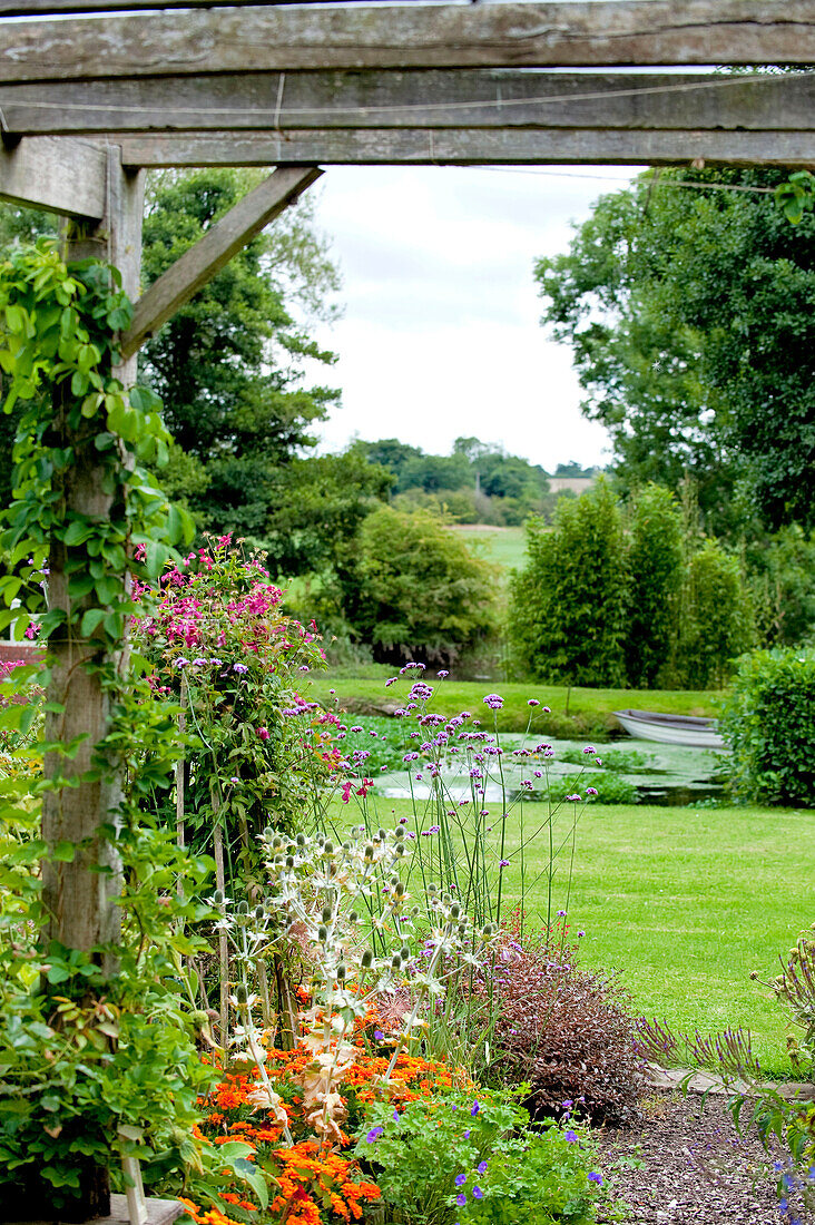 Blühende Pflanzen und Pergola im Garten eines Landhauses in Suffolk, England, UK