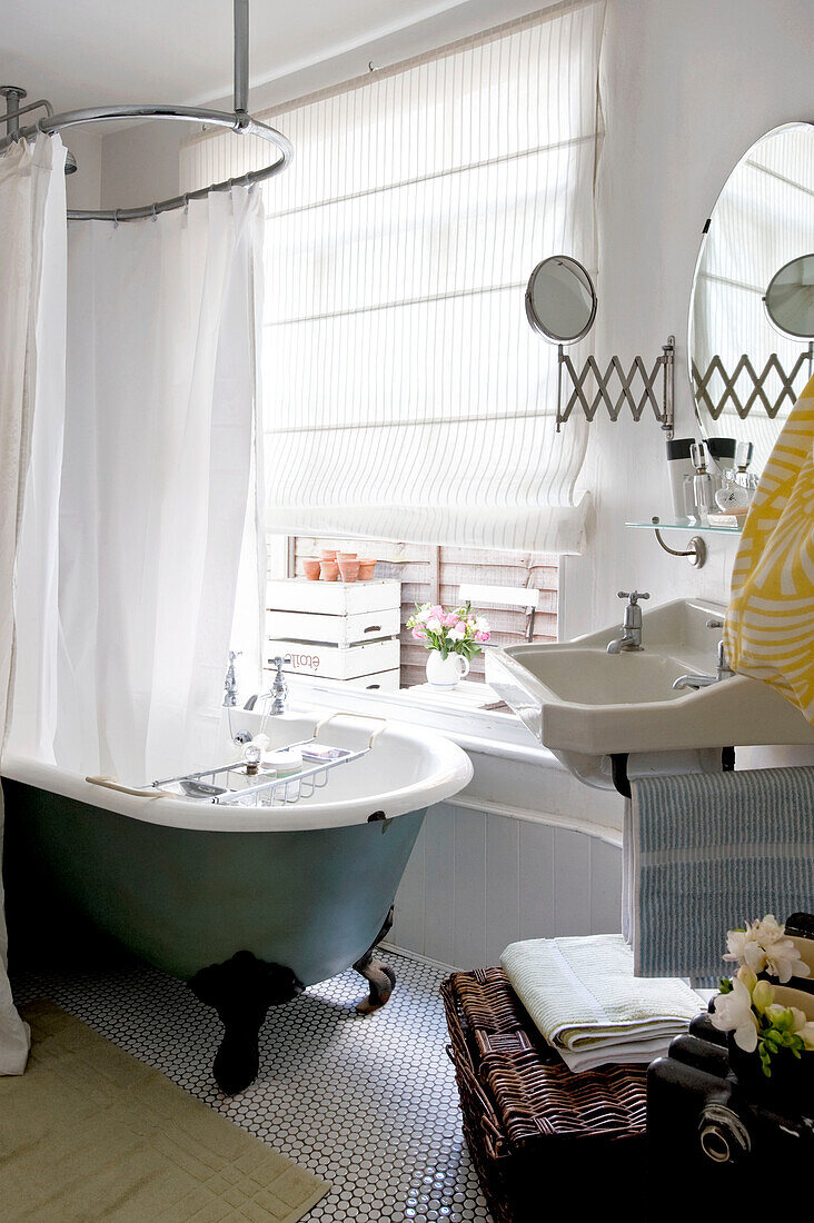 Bathroom with old fashioned shower rail above freestanding bath in London home, UK