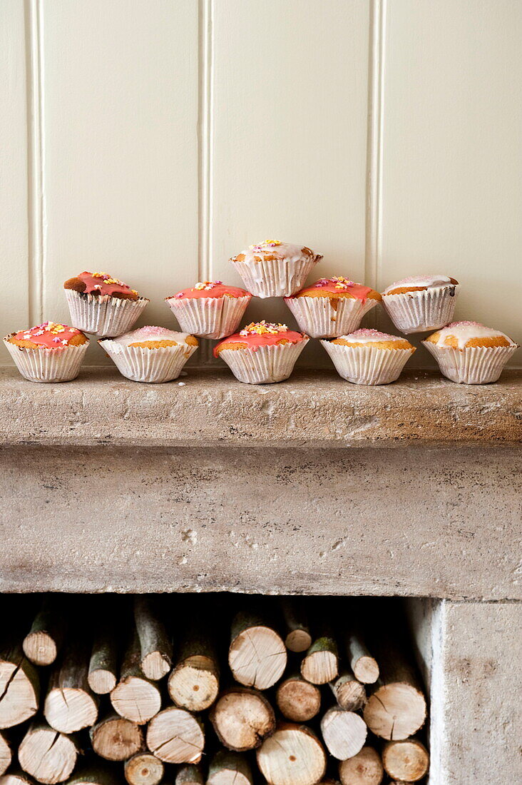 Handmade cupcakes with fireplace of logs in Buckinghamshire home, England, UK