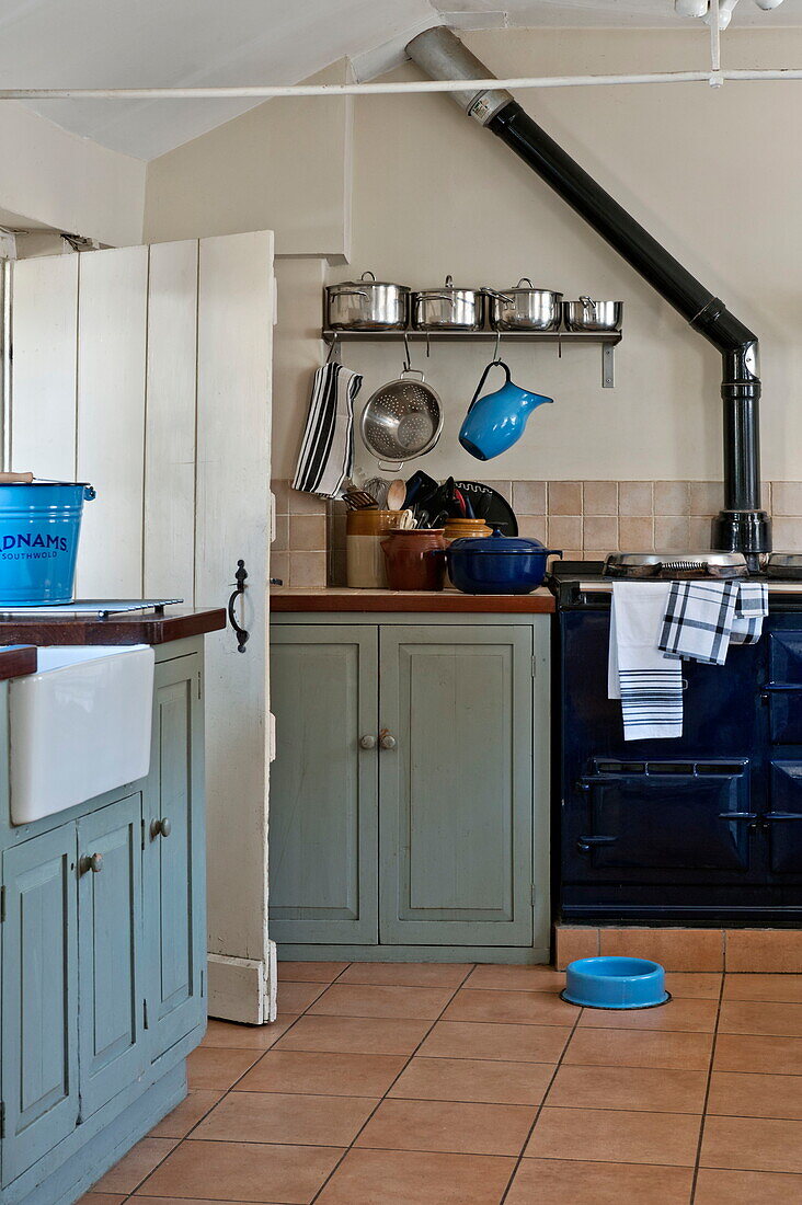 Bright blue kitchenware in tiled kitchen with painted units in Suffolk farmhouse, England, UK