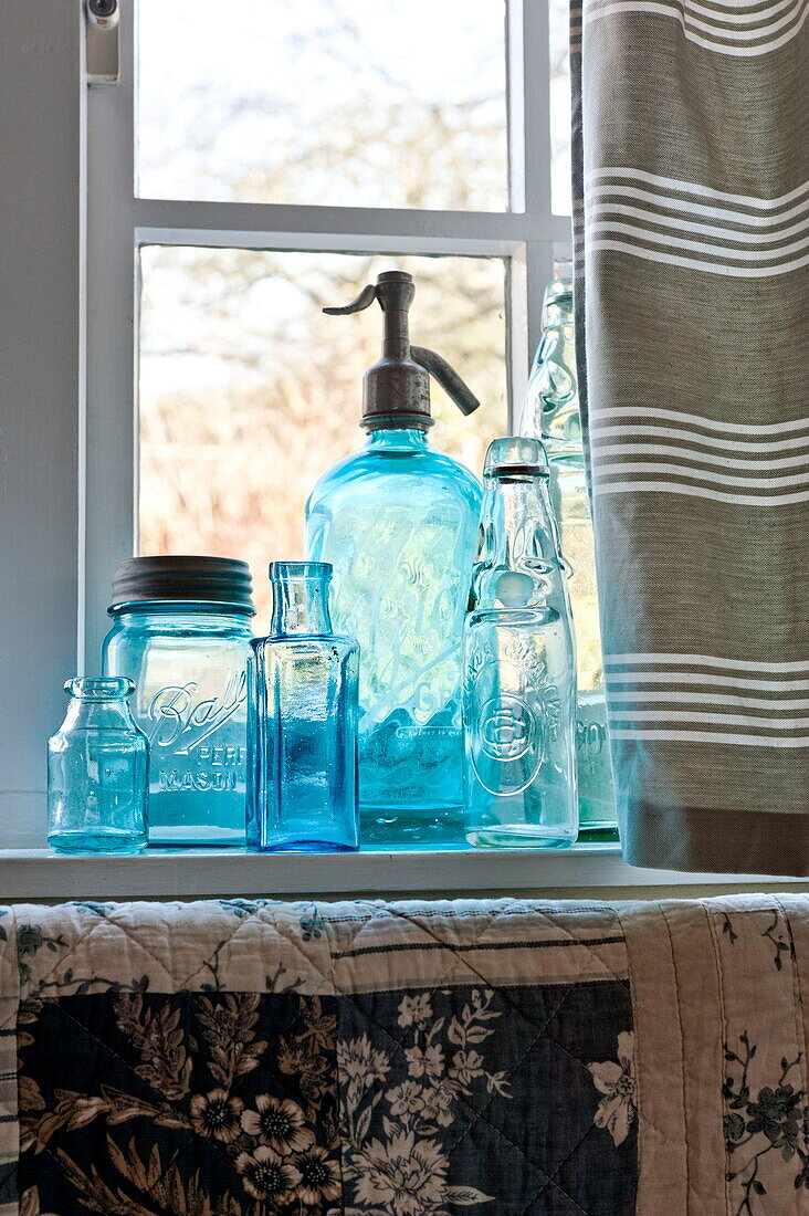 Glassware on window sill of Suffolk farmhouse kitchen, England, UK