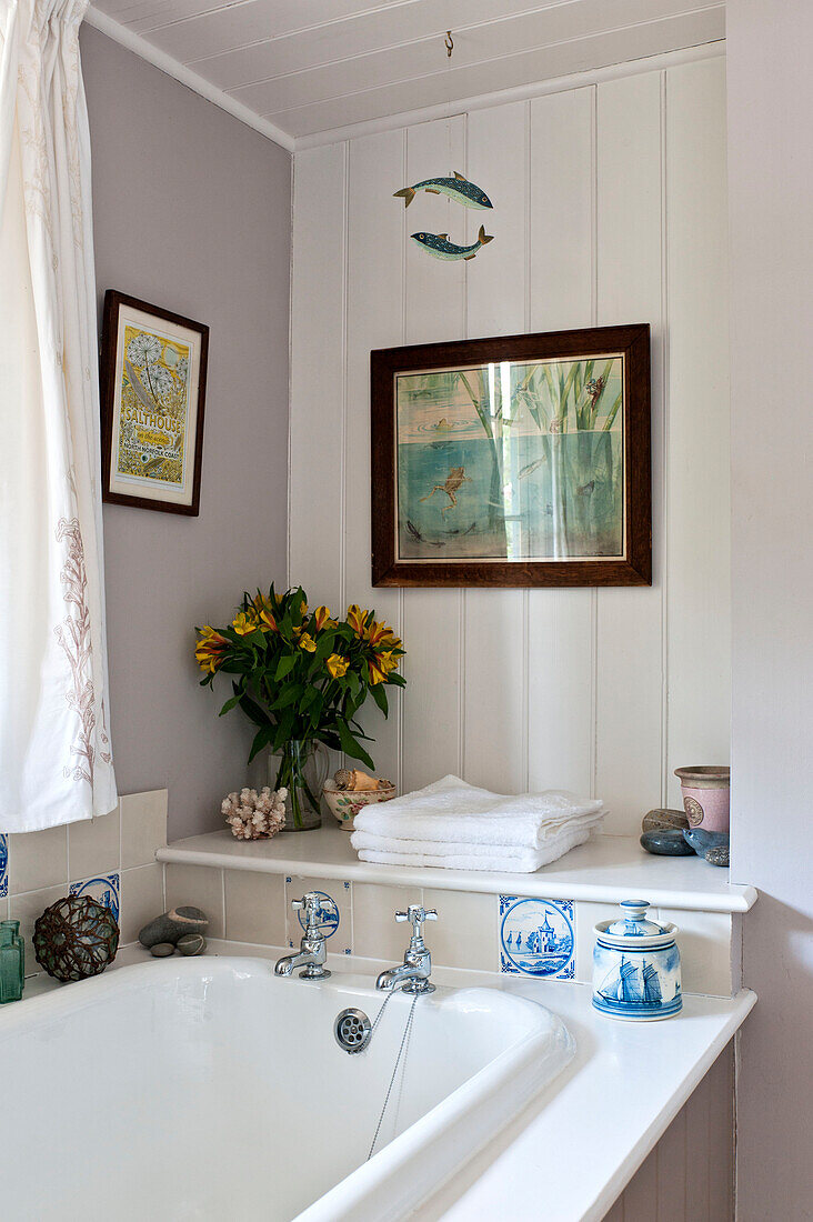 Cut flowers and ornaments with artwork, bathroom detail, Essex home, England, UK