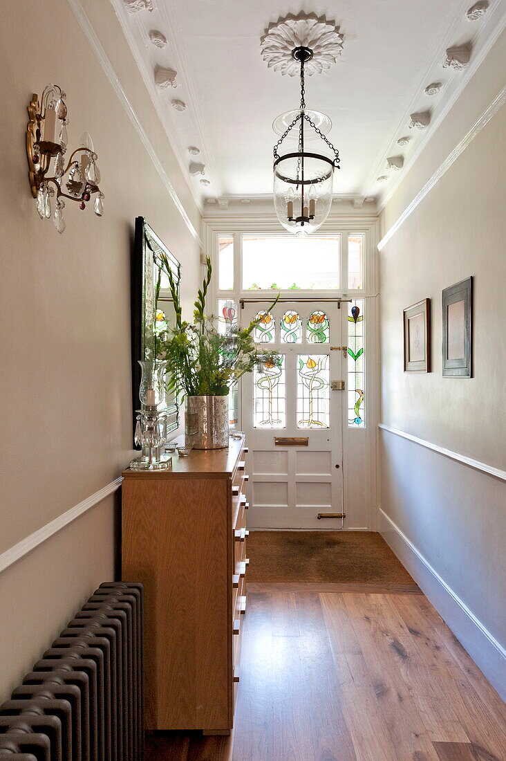 Stained glass front door with wooden floor in hallway of Middlesex family home, London, England, UK