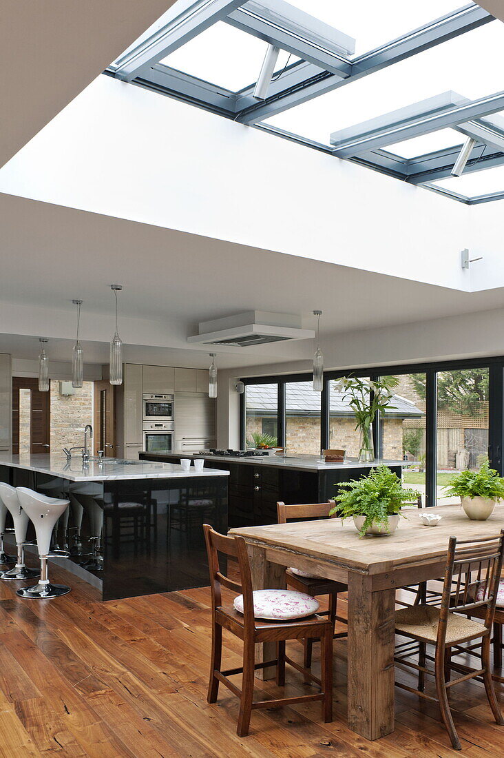 Wooden dining table and chairs in open plan dining room kitchen of London home, England, UK