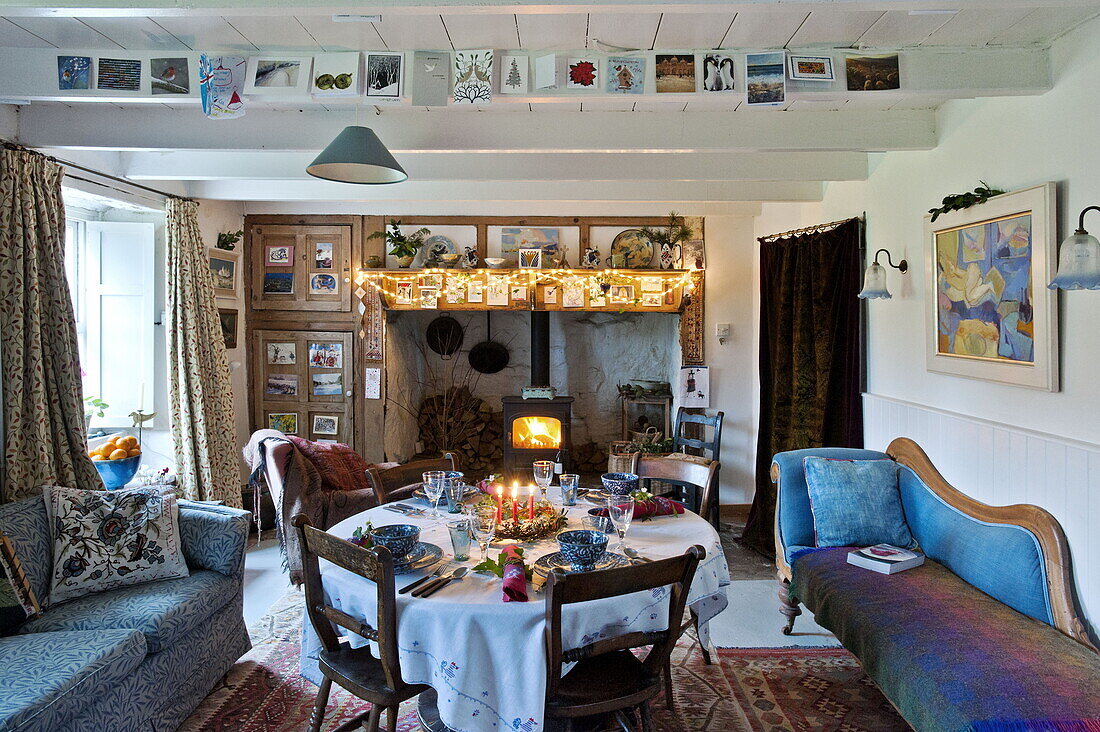 Lit candles on dining table at Christmas in farmhouse, Cornwall, England, UK