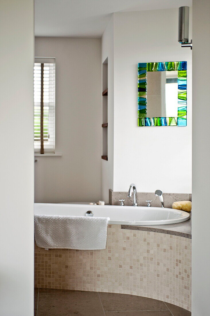 Mosaic tiled bath with stained glass mirror in contemporary home, Cornwall, England, UK