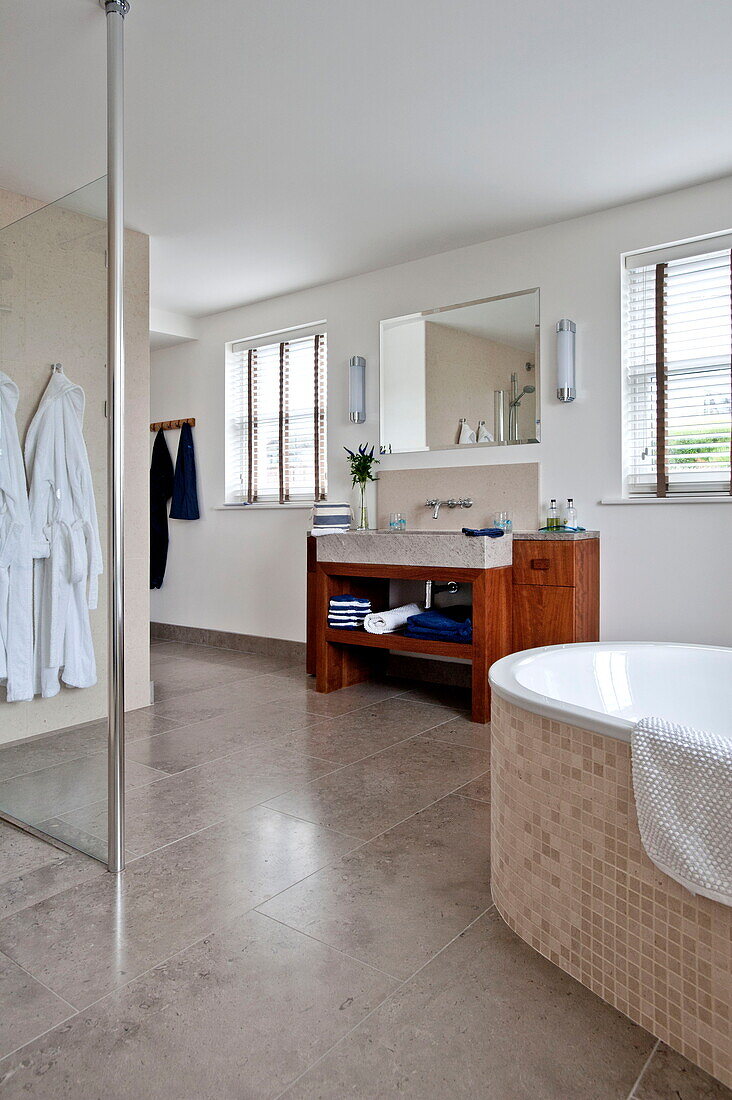 Bathrobes hang in spacious wet room with shower screen in contemporary home, Cornwall, England, UK