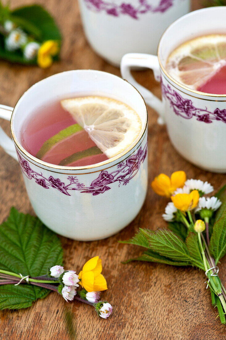 Cups with pink lemonade and posies of buttercups (Ranunculus) in Brecon, Powys, Wales, UK