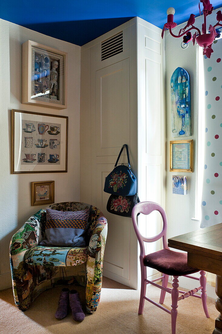 Gepolsterter Stuhl und Taschen mit Kunstwerken in einer Ecke eines Londoner Hauses, England, UK