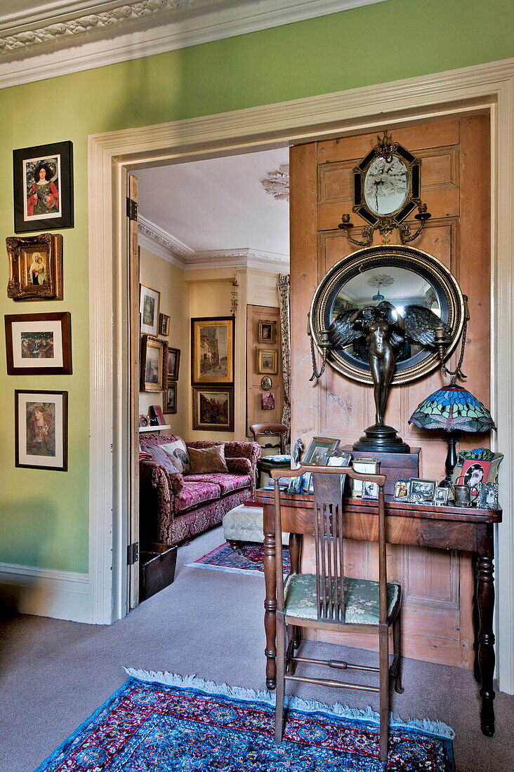 Convex mirror and winged figurine with desk and chair in London home, England, UK