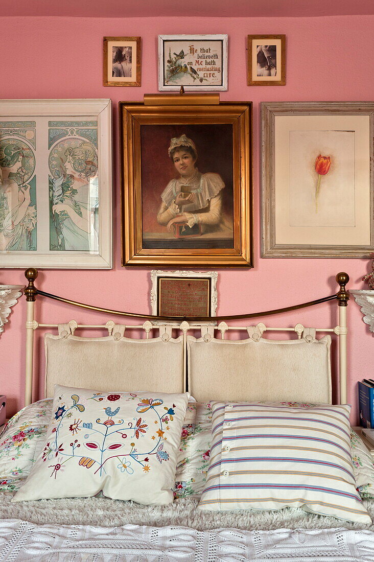 Messingbett und Kunstwerke im rosa Schlafzimmer eines Londoner Hauses, England, UK