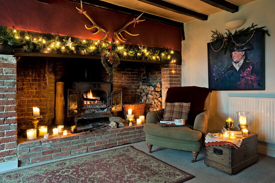 Lichterketten und brennende Kerzen im freiliegenden Ziegelsteinkamin in einem Cottage in Shropshire, England, UK