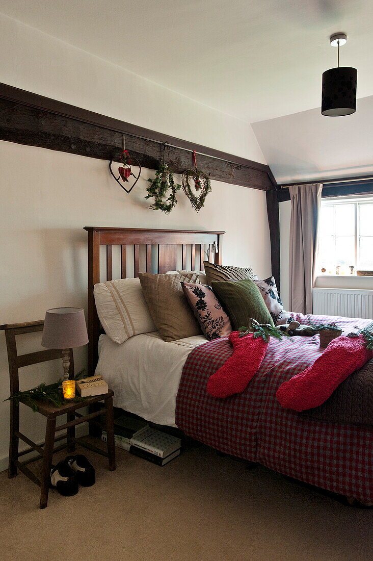 Weihnachtsstrümpfe auf einem Doppelbett mit einer brennenden Kerze in einem Bauernhaus in Shropshire, England, Vereinigtes Königreich