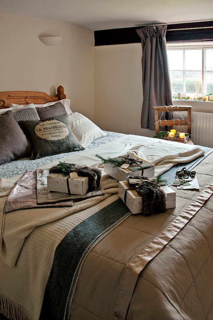 Gift wrapped presents on double bed in Shropshire cottage, England, UK