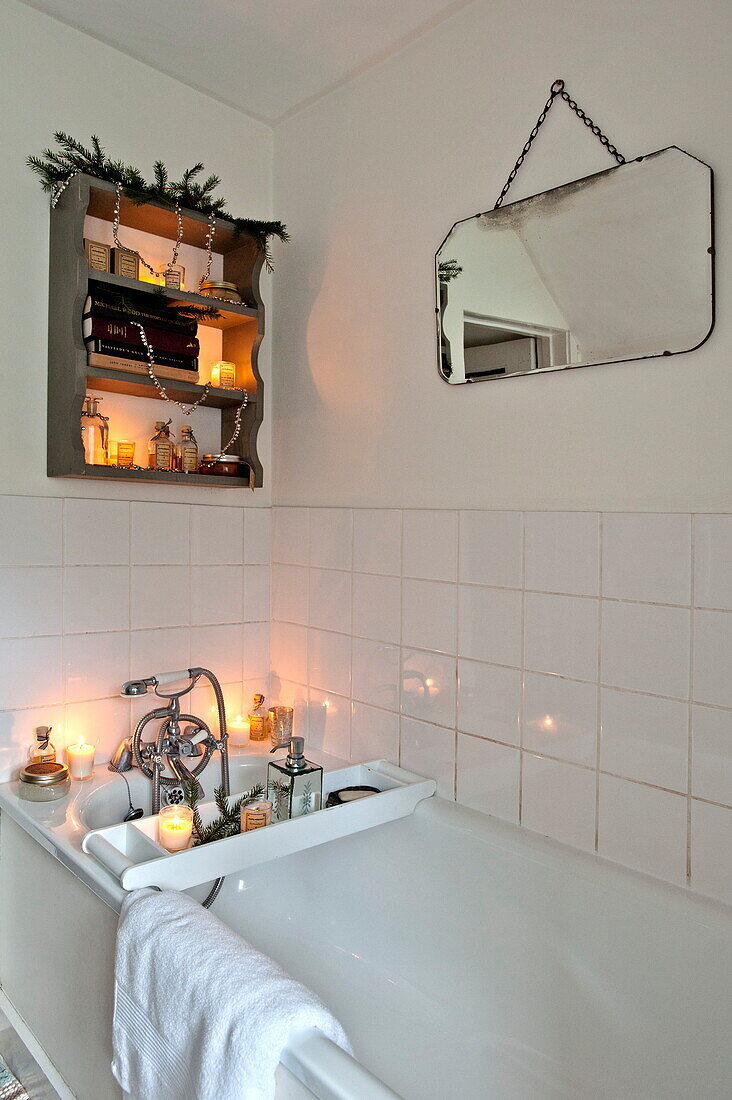 Lit candles in tiled white bathroom of Shropshire cottage, England, UK