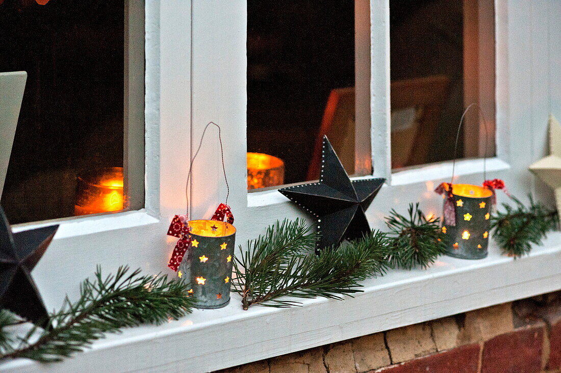 Beleuchtete Kerzen und Weihnachtsdekoration auf der Fensterbank eines Cottage in Shropshire, England, UK