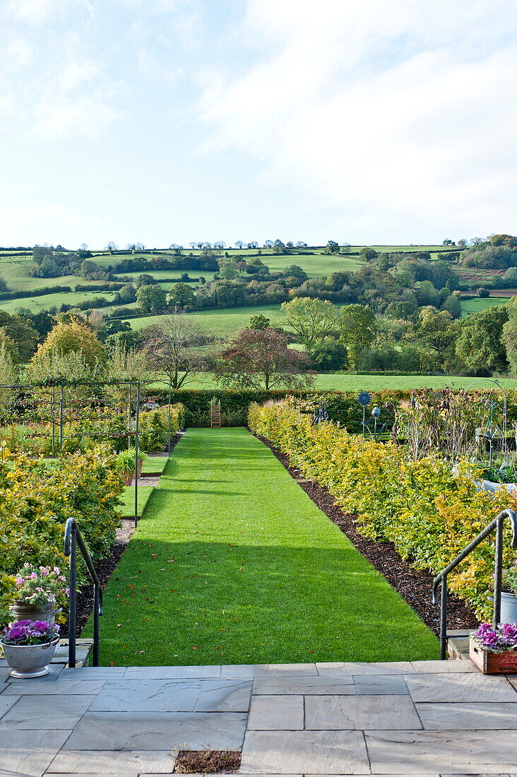 Paved patio and lawned exterior of garden in rural countryside, Blagdon, Somerset, England, UK