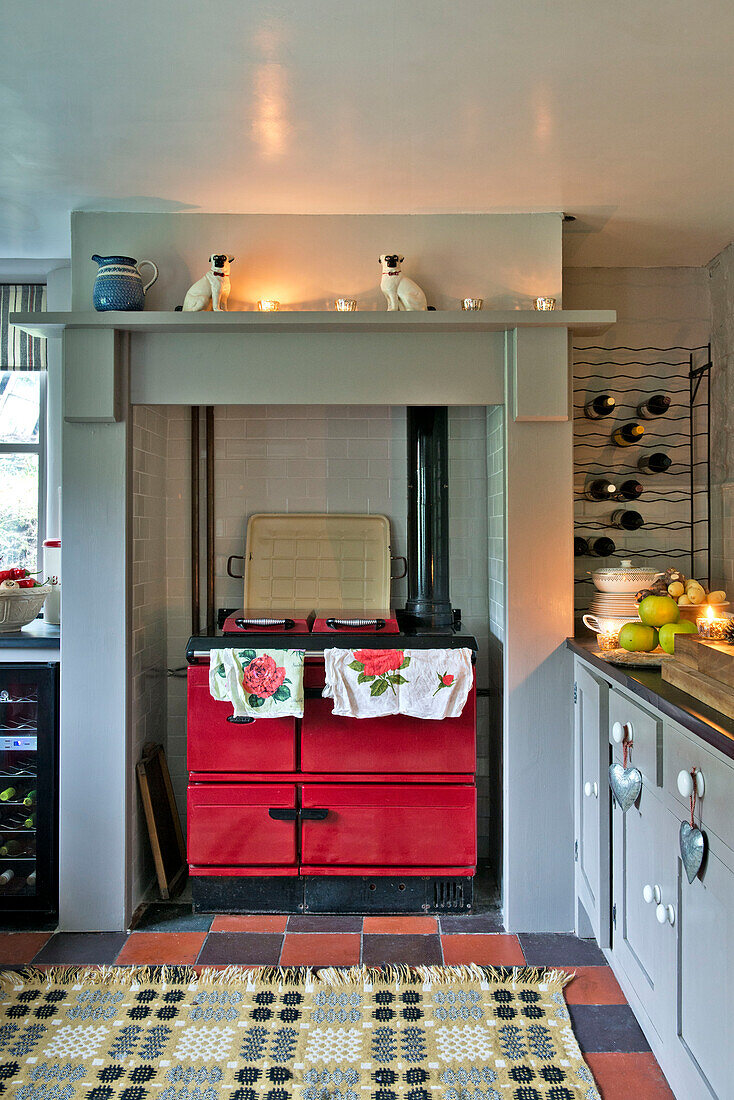 Lit tealights on shelf above red range oven with wine rack in kitchen of Tregaron home Wales UK