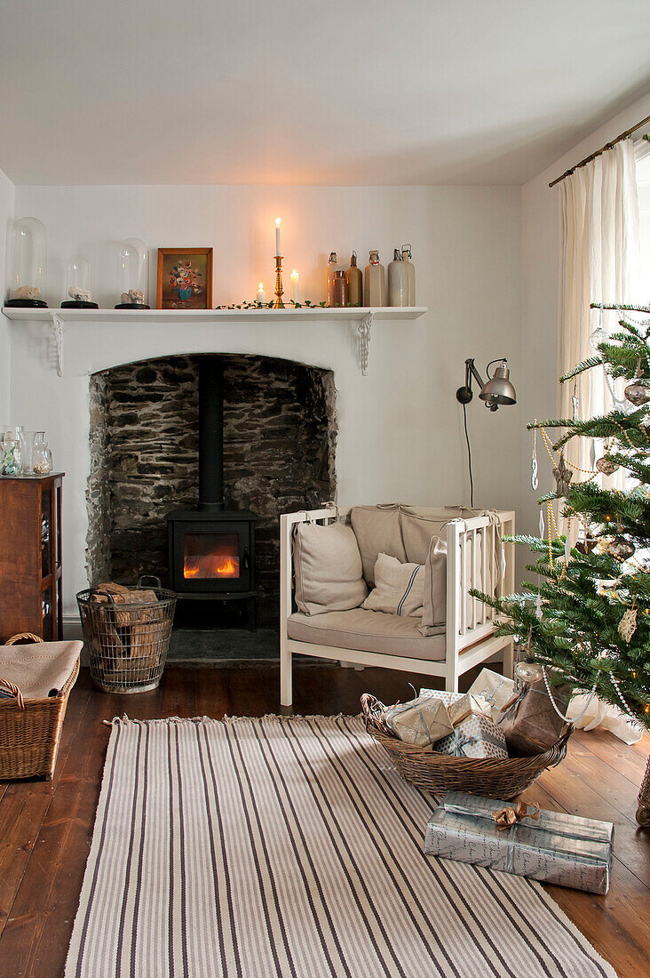 Weihnachtsbaum und Sessel vor dem Kamin in einem Haus in Crantock, Cornwall, England, Vereinigtes Königreich