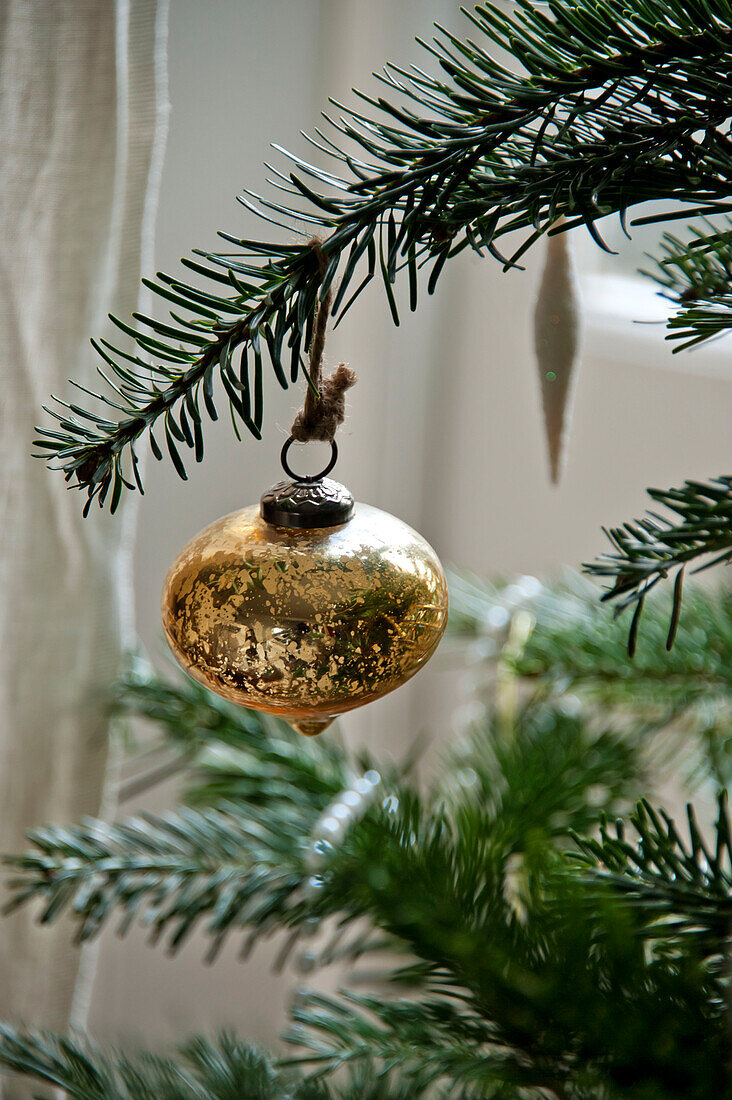 Goldene Metallkugel am Weihnachtsbaum im Haus in Crantock Cornwall England UK