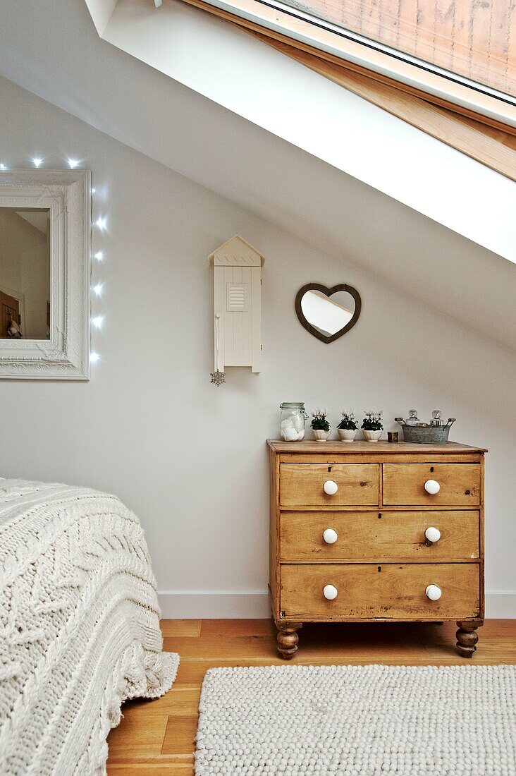 Herzförmiger Spiegel über einer hölzernen Kommode im Schlafzimmer im Dachgeschoss eines Familienhauses in Wadebridge, North Cornwall, UK