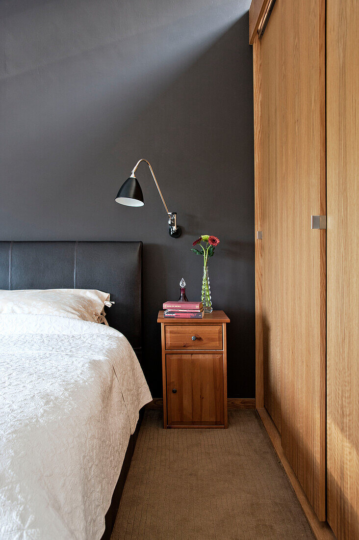 Wooden sliding door at bedside in Cornwall home, UK