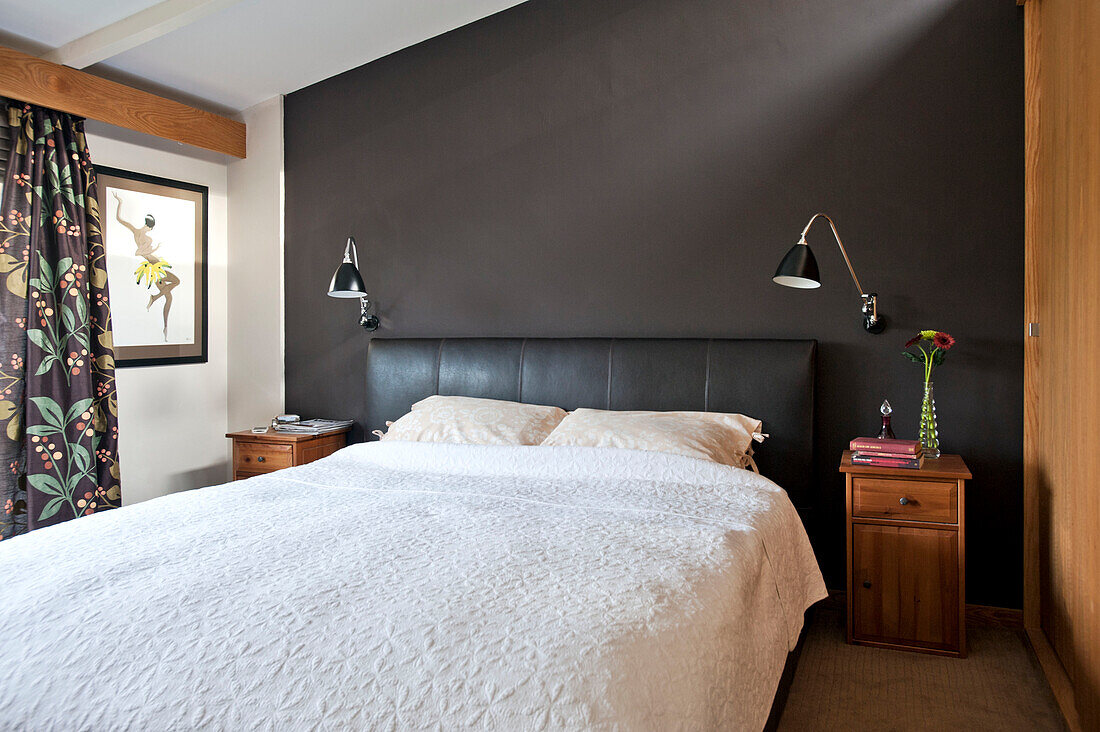 White bedspread with floral curtains in black bedroom of Cornwall home, UK