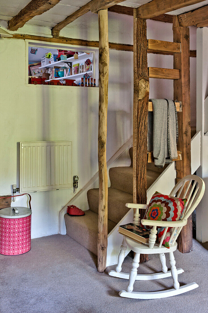 White painted rocking chair in rustic staircase of Cambridge cottage England UK