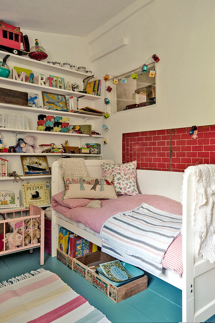 Single daybed with toys on open shelving in Cambridge cottage England UK