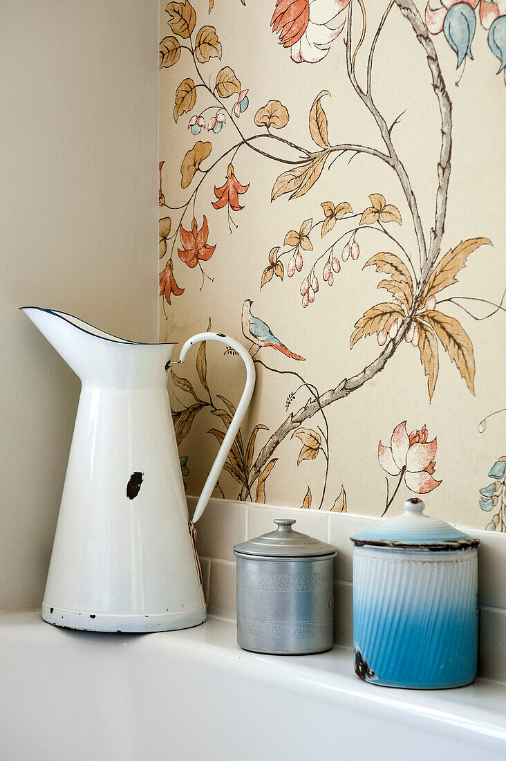 Metal jug and storage tins on bathside in Cambridge cottage England UK