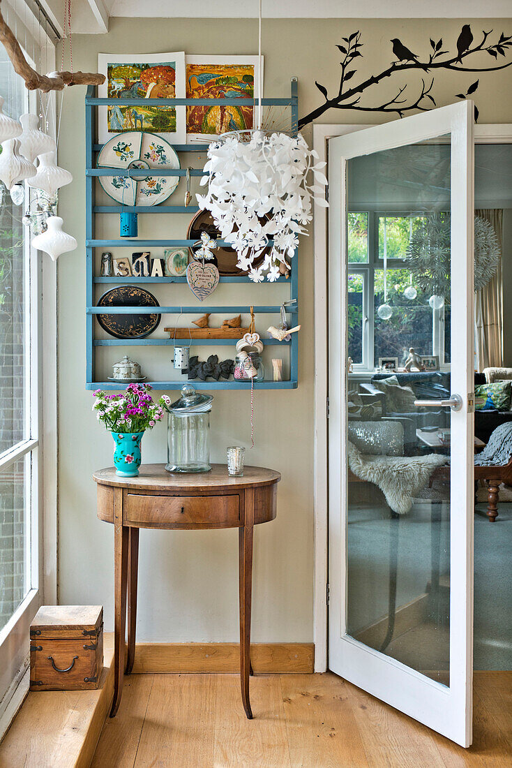 Wooden side table with glass door and wall-mounted shelving in East Grinstead family home West Sussex England UK