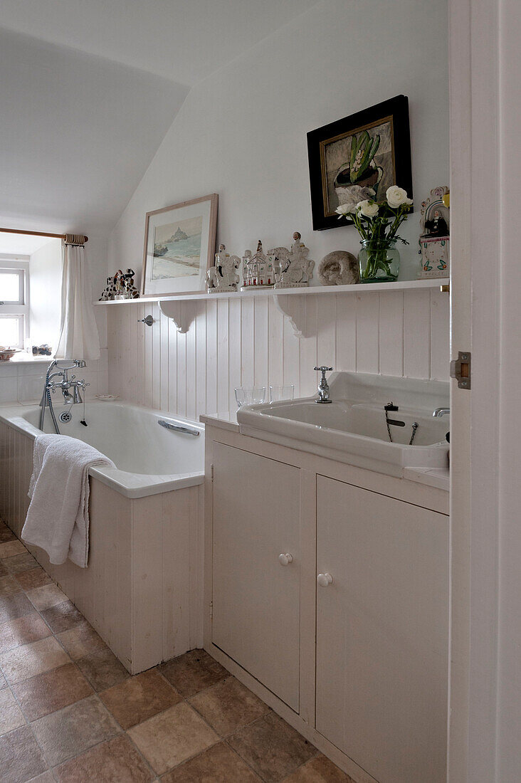 Weiß getäfeltes Badezimmer mit Ornamenten auf einem Regal in einem Strandhaus in Cornwall, England, UK