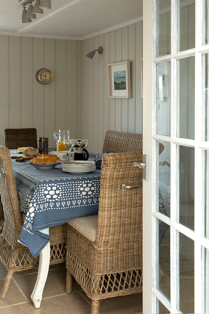 Breakfast table with wicker dining chairs in panelled Penzance farmhouse Cornwall England UK