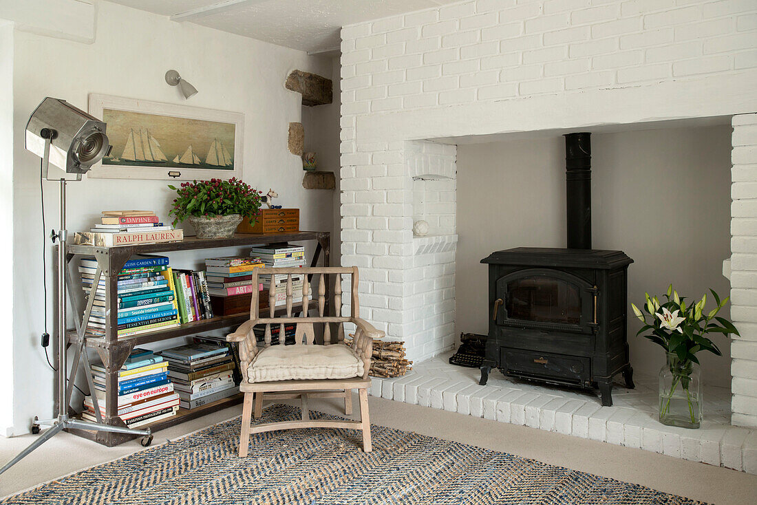 Wooden chair with bookcase and woodburner in Penzance farmhouse Cornwall England UK