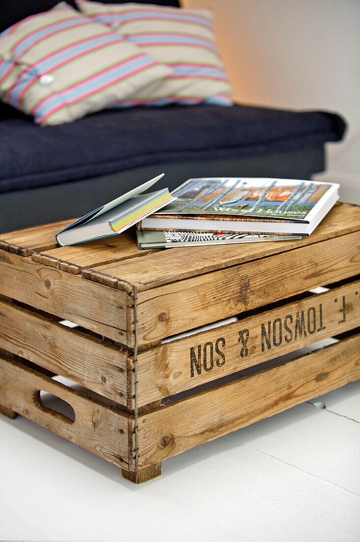 Books on crate with seating in family townhouse Cornwall England UK