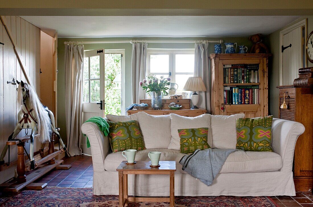 Cups on table in front of sofa with rocking horse in Edworth living room Bedfordshire England UK