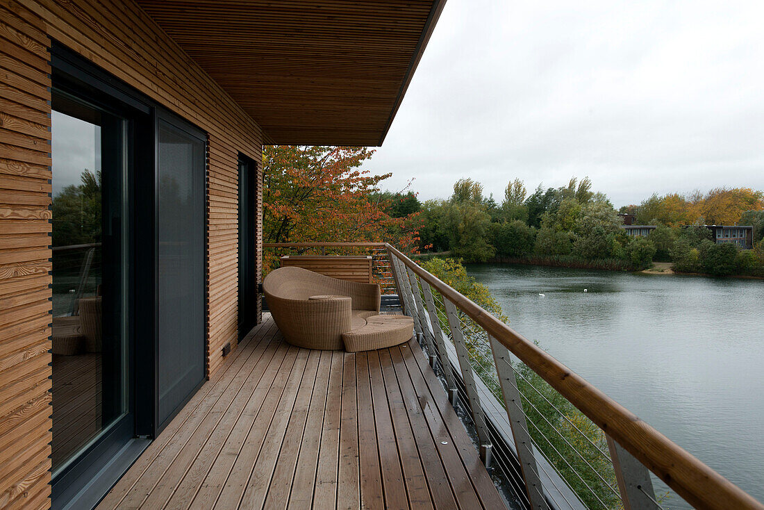 Wicker chair on veranda of remote lakeside house in Lechlade Gloucestershire England UK