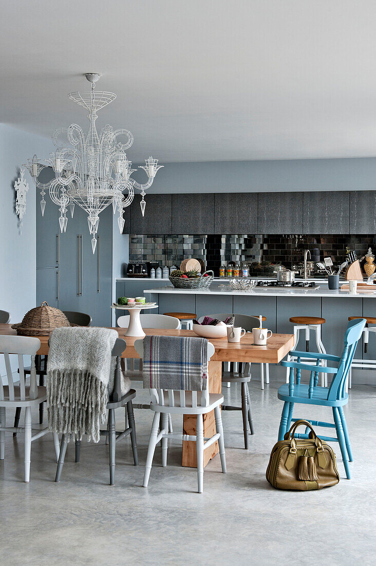 Leather bag and wooden dining table with chandelier in open plan Lechlade home Gloucestershire England UK