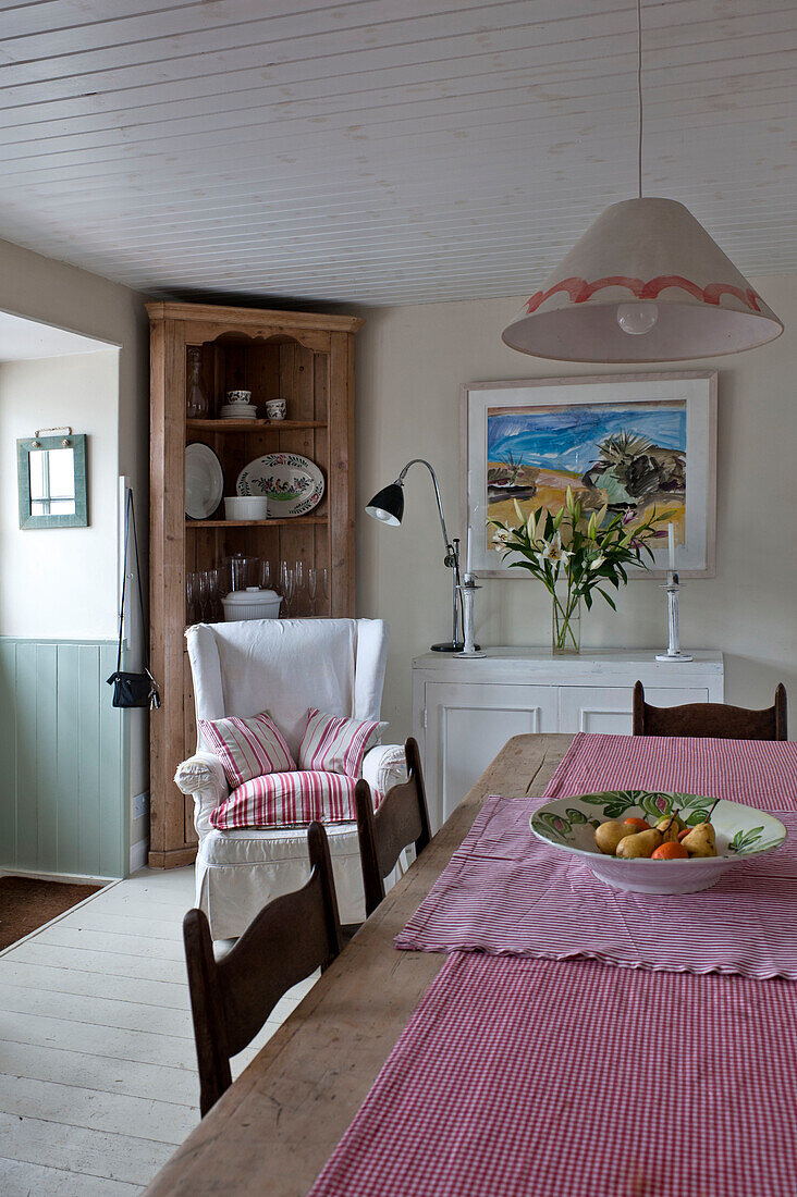 Holzeckschrank und Ohrensessel mit Küchentisch in Strandhausküche Cornwall England UK