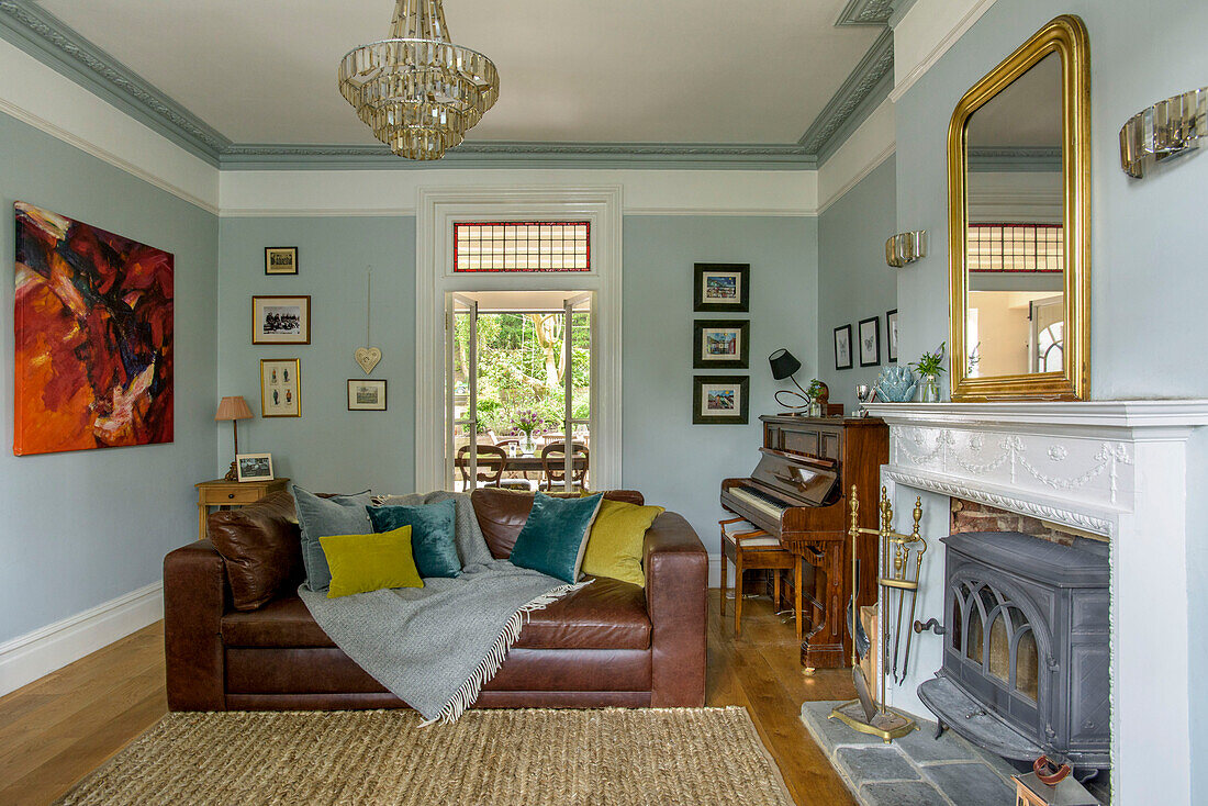 Brown leather sofa in light blue living room with glass chandelier Tunbridge Wells family home Kent England UK