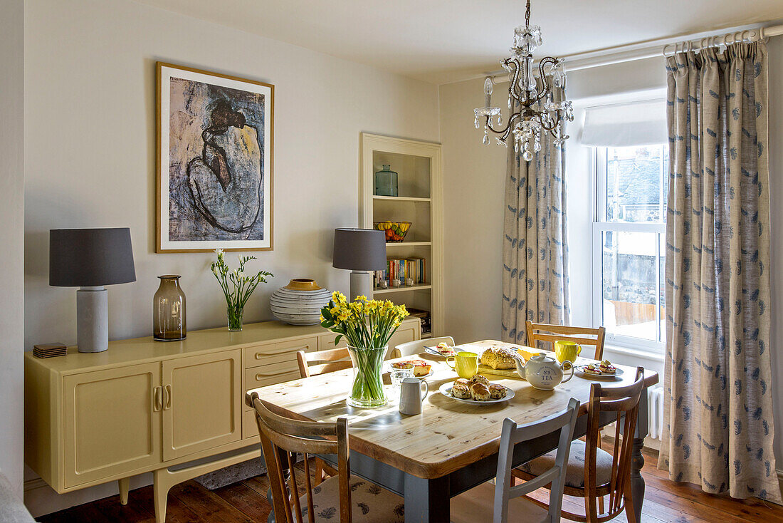 Afternoon tea on dining table below chandelier in St Ives home Cornwall UK