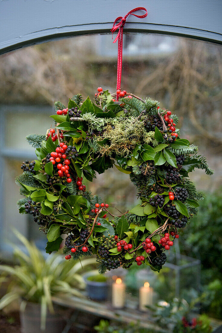 Weihnachtskranz aus Blättern und Beeren im Fenster eines Hauses in Penzance, Cornwall, UK