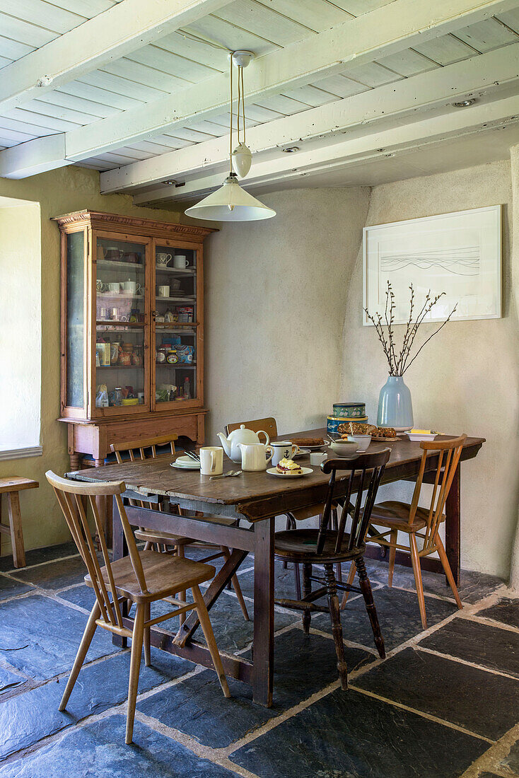 Wooden chairs and dresser with table set for afternoon in Helston farmhouse kitchen Cornwall UK