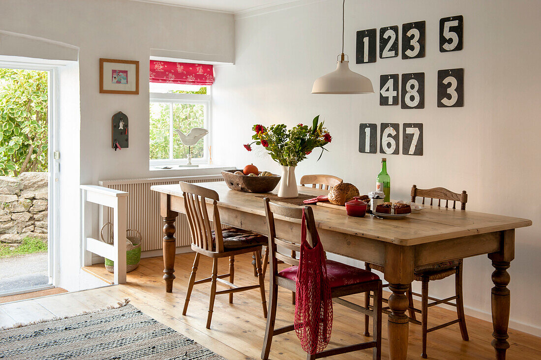 Esstisch aus Holz mit Zahlen auf der Anzeigetafel und offener Hintertür in einem Ferienhaus in Cornwall UK